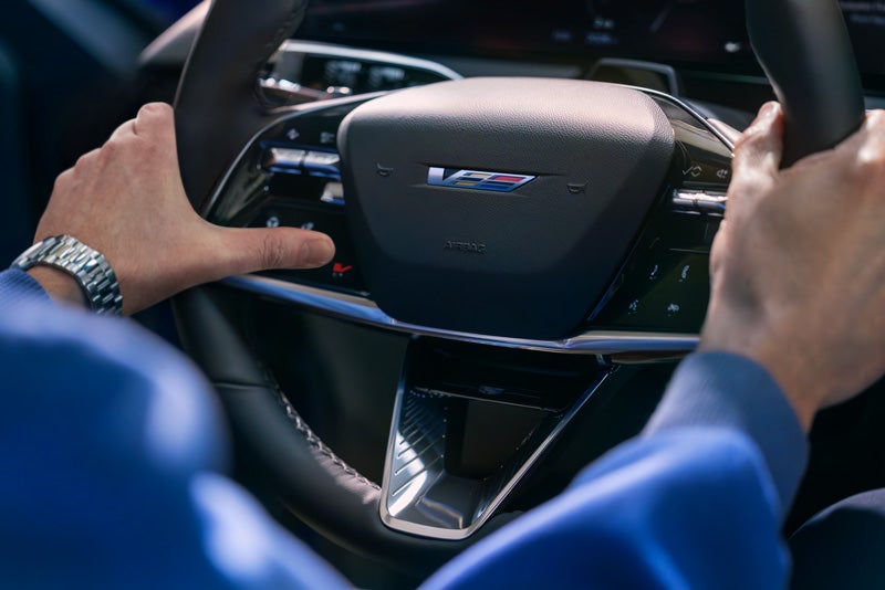 Close-up of a Man About to Press the V-Button on the 2026 OPTIQ-V Steering Wheel | Tom Naquin Cadillac in Elkhart IN