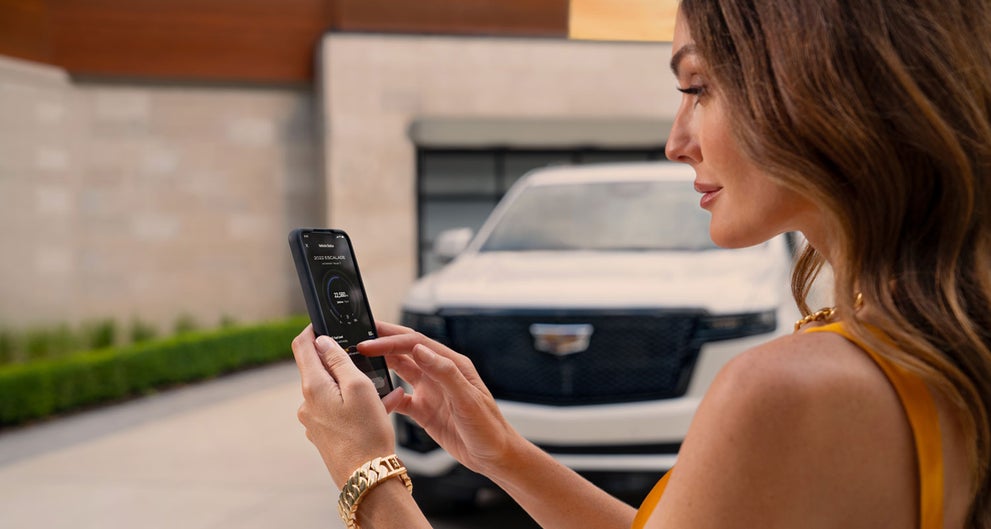 lady checking her mobile with a Cadillac vehicle background | Tom Naquin Cadillac in Elkhart IN